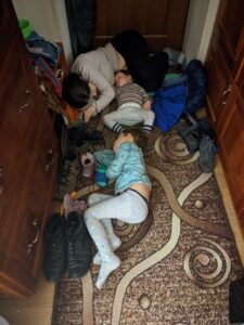 Woman and two children sleeping on the floor in a hallway